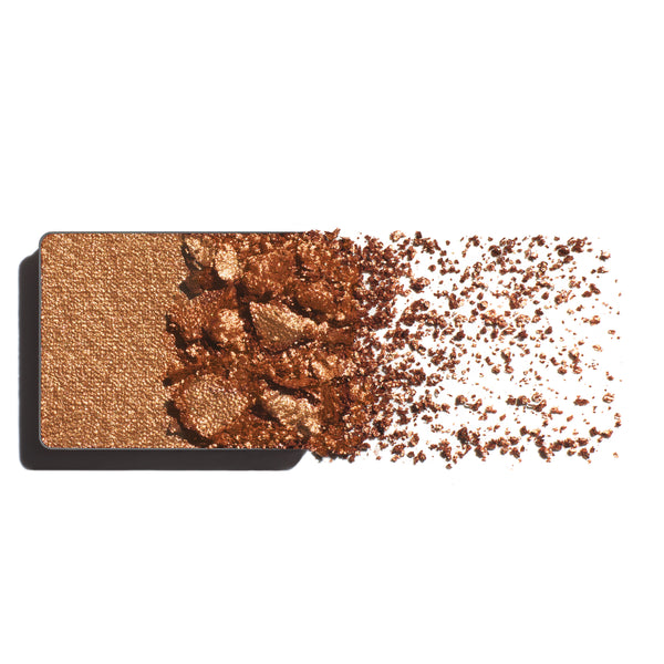 Makeup eyeshadow refill with ginger-gold powder on a white background