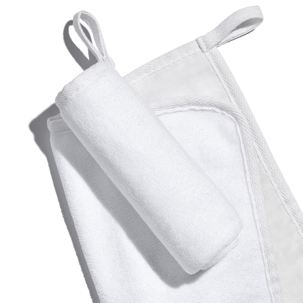White, banded, Lisa Eldridge Luxuriously Gentle Cleansing & Exfoliating Cloth, one flat and one rolled up on top, showing different textures of the cloth faces and a loop for hanging up