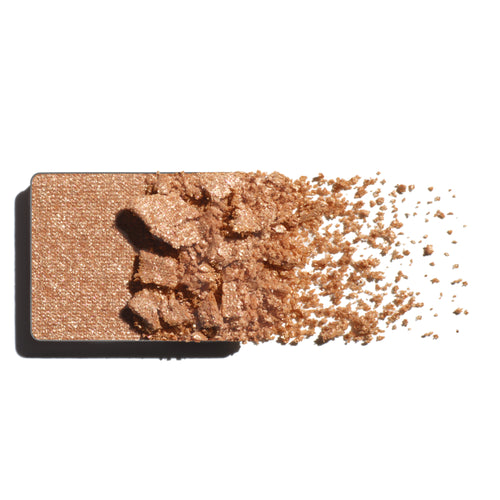 Makeup eyeshadow refill with light gold shimmer powder on a white background